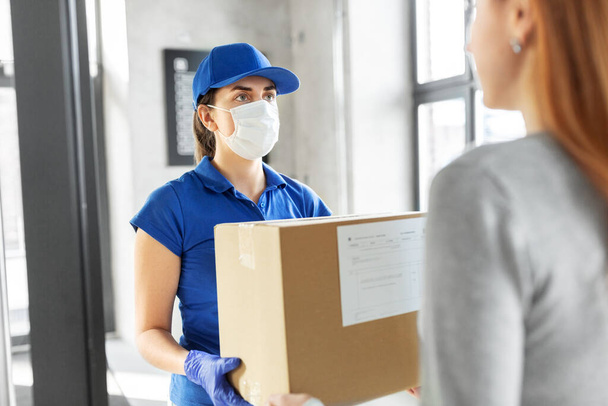 delivery girl in face mask giving parcel to woman - Foto, immagini