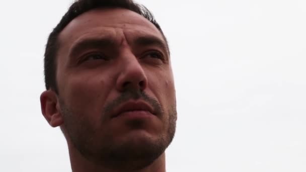 A close-up of the face of a man looking into the distance against the sky. - Кадри, відео