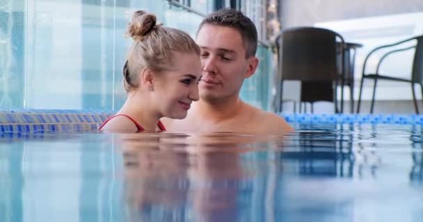 blondýny úsměvy ponořené v modrém bazénu vody v blízkosti člověka - Záběry, video