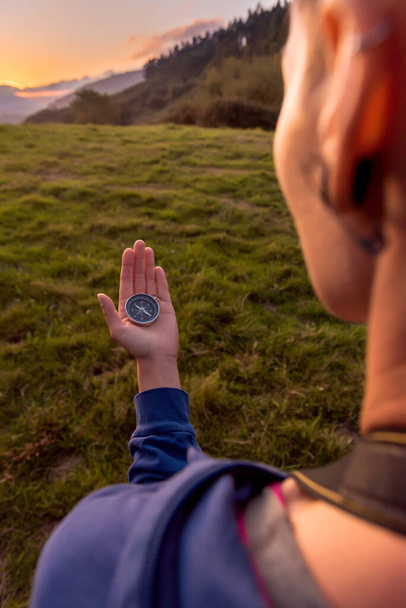A nő mágneses iránytűt használ, hogy megtalálja az utat a hegyekben naplementekor. Kalandkoncepció. - Fotó, kép