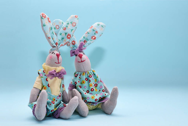 Un par de coloridos conejos de Pascua de tela hechos a mano aislados sobre fondo de menta azul claro. Decoraciones de Pascua
. - Foto, imagen