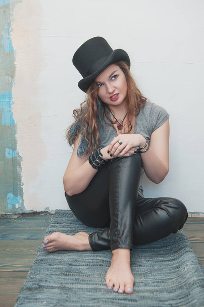 Divatos divatos hipster nő kalapban, kezekkel a mezítlábas lábakon - Fotó, kép