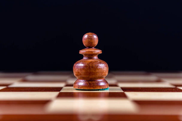 black wooden pawn on a chessboard on a black background - Φωτογραφία, εικόνα