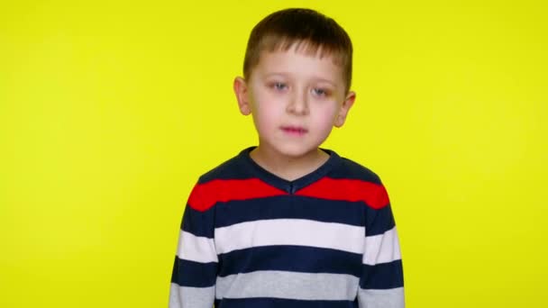 Menino criança grave em uma camisola colorida diz sim em um fundo amarelo
 - Filmagem, Vídeo