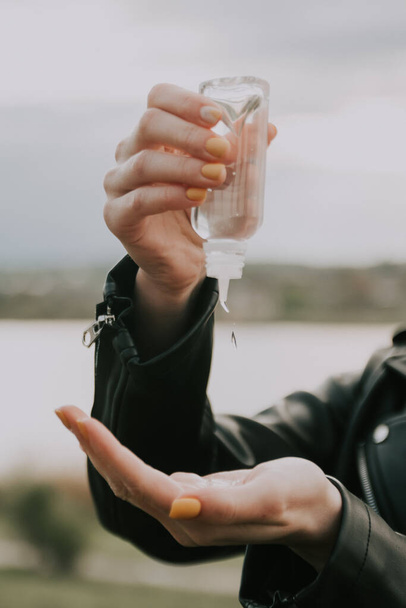 дівчина п'є антисептик на руці
 - Фото, зображення