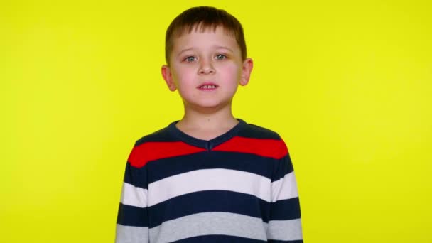 Θυμωμένο μικρό αγόρι γρυλίζει στην κάμερα σε ένα κίτρινο φόντο με αντίγραφο χώρο - Πλάνα, βίντεο