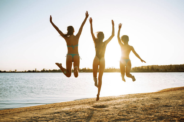 Glückliche Mädchen springen am Strand. Sommerurlaub, Urlaub, Entspannung und Lifestylekonzept. - Foto, Bild