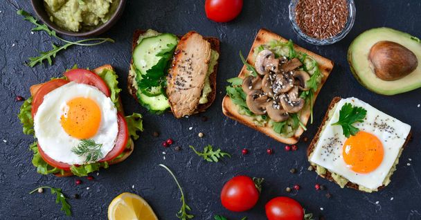 Verschiedene Sandwiches auf schwarzem Hintergrund. Leckere gesunde Vorspeise mit Avocado. Schnelles Frühstück. Konzept für gesunde Ernährung. Richtige Ernährung. Ansicht von oben.  - Foto, Bild