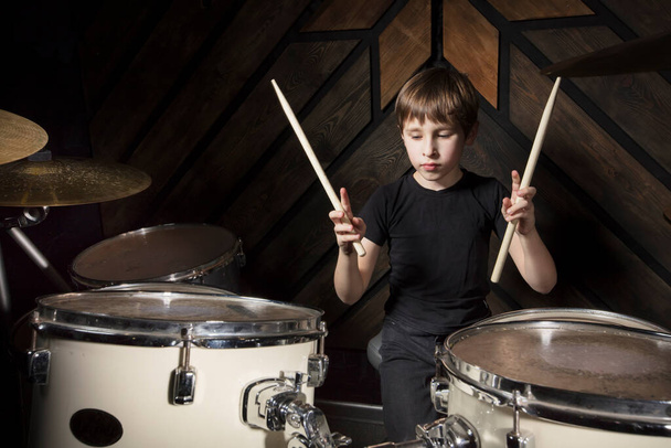 A boy is playing with a drumstick. The child behind the drum kit. - Photo, Image