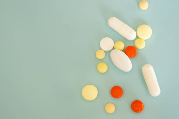 veelkleurige pillen van verschillende vormen op een blauwe achtergrond, geneesmiddelen op recept, op een blauwe achtergrond met plaats voor uw tekst - Foto, afbeelding