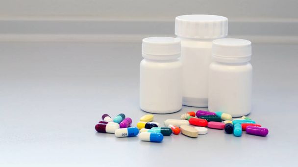 Mock up weißen Medizinflaschen mit bunten Tabletten, Pillen und Kapseln Medikamente zur Behandlung und Heilung der Krankheit oder Krankheit. Medikamentenverschreibung für Medikamentenisolat vor weißem Hintergrund. - Foto, Bild