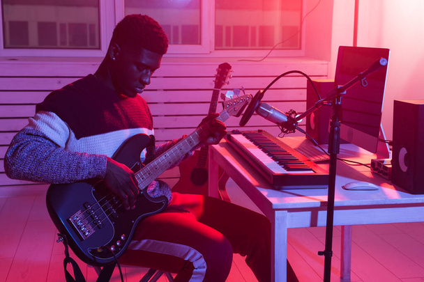 Δημιουργήστε μουσική και μια ιδέα στούντιο ηχογράφησης - Αφρικανός Αμερικανός κιθαρίστας ηχογράφησης ηλεκτρικό κομμάτι κιθάρας στο στούντιο του σπιτιού - Φωτογραφία, εικόνα