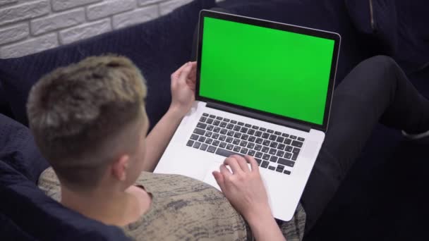 laptop zöld képernyő mockup, férfi használ laptop, pihentető kanapén otthon - Felvétel, videó