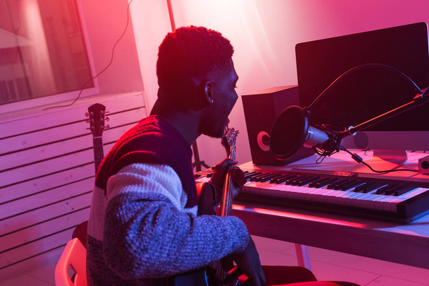 Músico profesional afroamericano grabando bajo en estudio digital en casa, concepto de tecnología de producción musical
. - Foto, Imagen