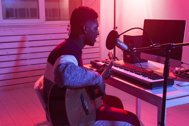 Afroamerikaner professioneller Musiker nimmt Gitarre im digitalen Studio zu Hause auf, Konzept der Musikproduktionstechnologie. - Foto, Bild