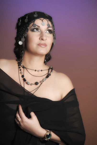 schöne brünette Frau in schwarzen orientalischen Kleidern mit Turban und Ornamenten auf dem Kopf - Foto, Bild