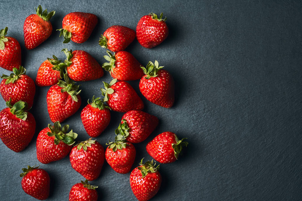 Draufsicht auf einige rote Erdbeeren auf dunklem Hintergrund. - Foto, Bild