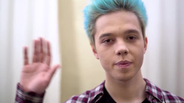 Giovane uomo che agita la mano, guardando la fotocamera ritratto da vicino, ragazzo capelli blu
 - Filmati, video