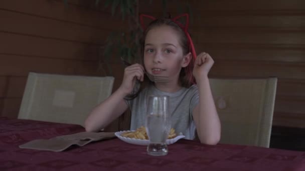 Mała dziewczynka jedząca frytki w restauracji fast food. Dziewczyna je frytki. Mała dziewczynka je lunch w kawiarni.. - Materiał filmowy, wideo