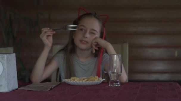 Menina comendo batatas fritas no restaurante fast food. Rapariga a comer batatas fritas. Menina almoça em um café
. - Filmagem, Vídeo