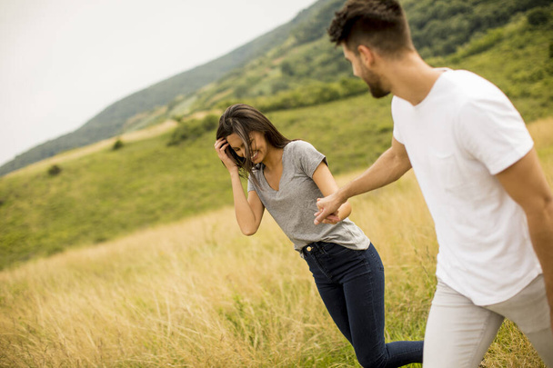 Felice giovane coppia innamorata a piedi attraverso il campo di erba - Foto, immagini