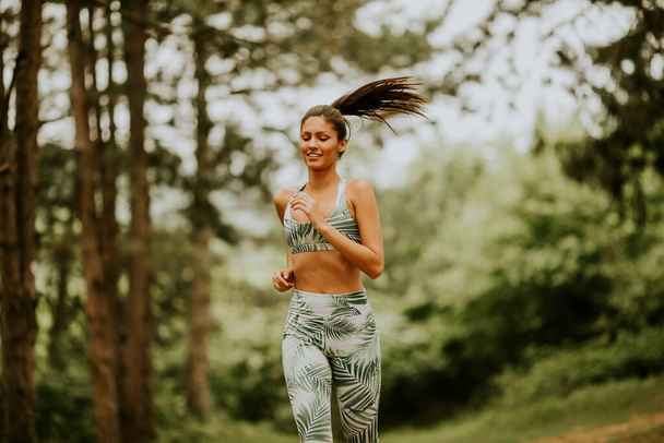 Mulher fitness muito jovem correndo na trilha da floresta - Foto, Imagem