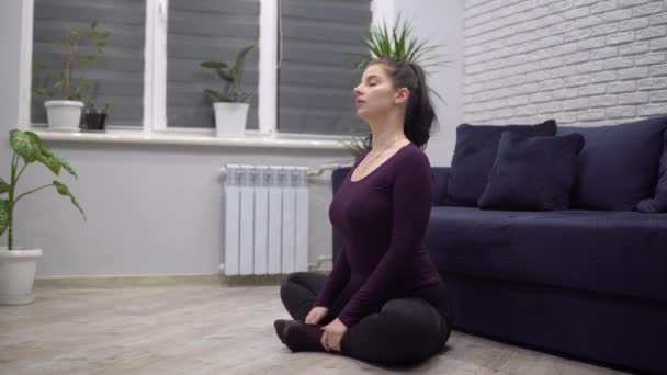 Mladá atraktivní žena dělá sportovní jóga cvičení meditace doma lotus asana - Záběry, video