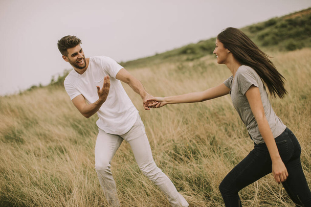Heureux jeune couple amoureux marchant à travers le champ d'herbe - Photo, image