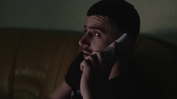 Dissatisfied angry man talking on phone with food pizza delivery courier at night at home in apartment. Poor customer service. Nervous person communicates with their friend or girlfriend. Night TV - Materiał filmowy, wideo