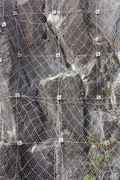 Nahaufnahme des Berghangs mit einem Steinschlagschutznetz, das verhindert, dass Steine auf die Straße fallen - Foto, Bild