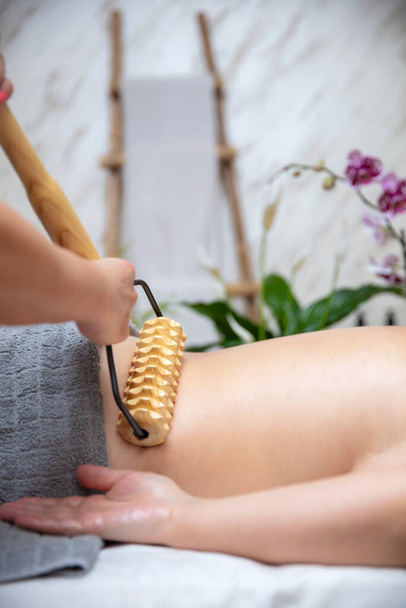 Fechar a massagem anti-celulite de maderoterapia com massageador de rolos de madeira
 - Foto, Imagem