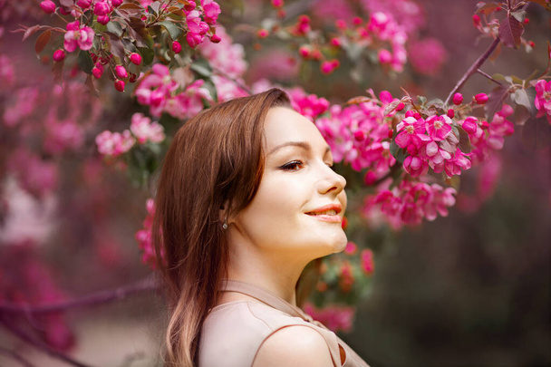 portrait of a beautiful young woman with make-up near a tree with flowers - Photo, Image