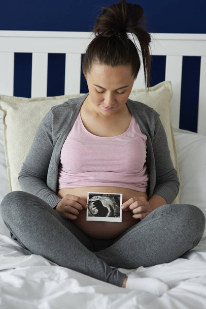 Těhotná žena drží ultrazvuk obraz na břiše - Fotografie, Obrázek