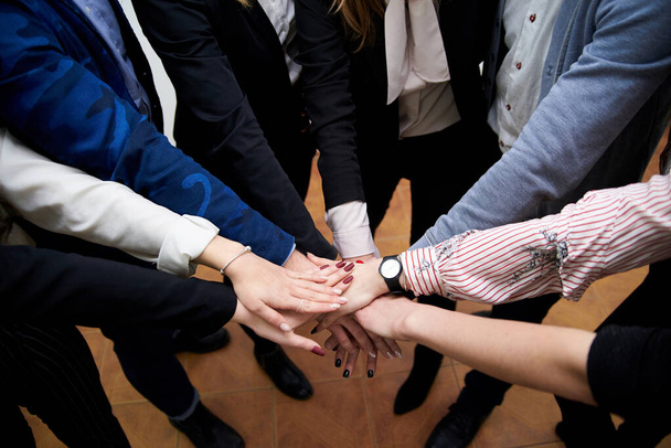 Team building process in company with young progressive people. Work meeting in office that include voting and making decision. Hands of people, held together in the middle. - Photo, Image