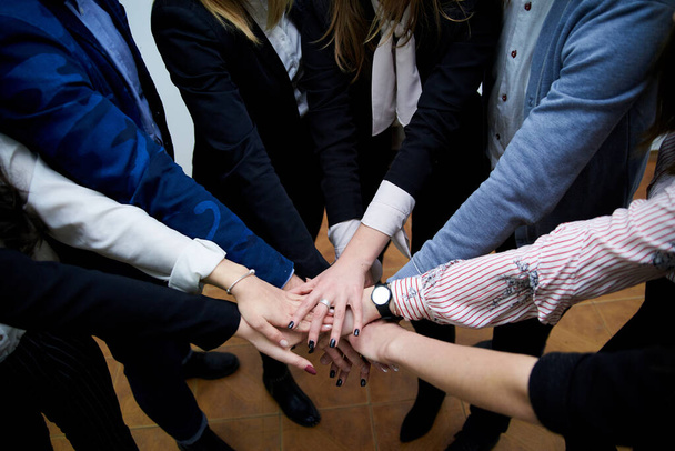 Team building process in company with young progressive people. Work meeting in office that include voting and making decision. Hands of people, held together in the middle. - Photo, Image