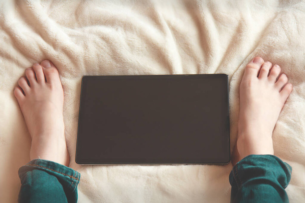 Adolescente sentado en la cama y mirando la pantalla de la tableta
 - Foto, imagen