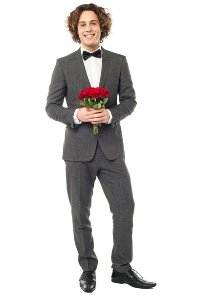 Groom in tuxedo posing with a bouquet - Фото, зображення