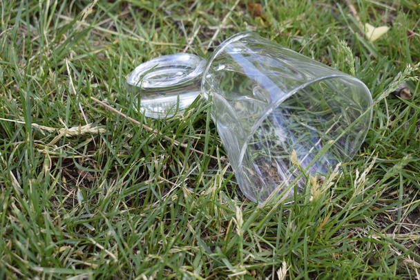 Copa de vidrio roto en la hierba verde en el jardín. Fondo grueso roto del vidrio
. - Foto, Imagen