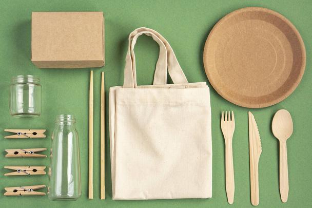 Zero Waste Cotton Bag. Zero waste concept. Textile eco bag, glass jars, wooden kitchen accessories on green background. Eco friendly and reuse concept. Top view, flat lay.  - Fotó, kép