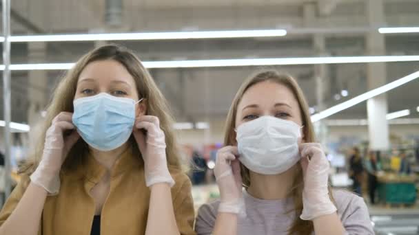 Vrouwelijke vrienden verwijderen graag medische maskers en knuffelen elkaar in de supermarkt. De coronaviruspandemie is voorbij.. - Video