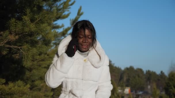 meisje met zwarte huid wandelingen langs bos en praat over de telefoon - Video