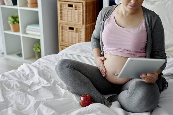 Těhotná žena kontroluje něco na tabletu - Fotografie, Obrázek