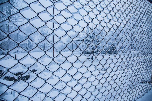 Drótkerítés a hóban. Kerítés háttér. Fémháló hóval. Fémháló télen hóval borítva. Drótkerítés közelről. Acél drótháló kerítés vintage hatás. - Képet. - Fotó, kép