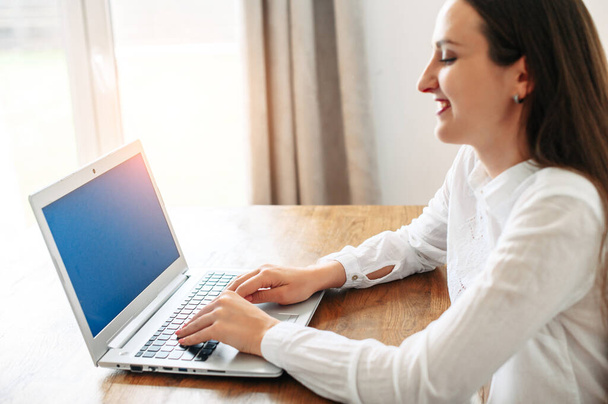 A young woman in smart casual white shirt using laptop - Zdjęcie, obraz