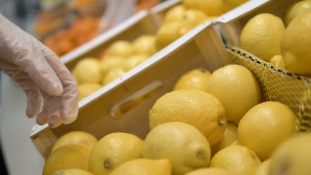 Девушка в медицинских перчатках выбирает лимон в супермаркете. индивидуальная защита кокороновируса, витамин С
 - Кадры, видео
