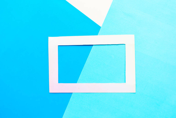 White photo frame on geometric blue background. Copy space for the space. Minimal concept - Foto, imagen