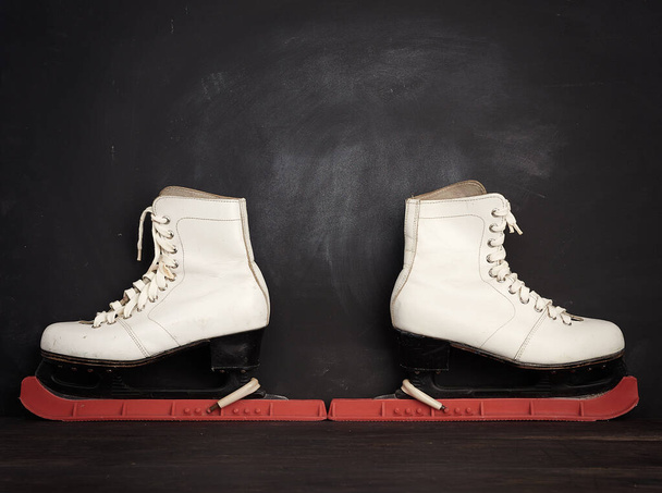 witte leren schaatsen voor kunstschaatsen op een bruine houten ondergrond, sportuitrusting, kopieerruimte - Foto, afbeelding