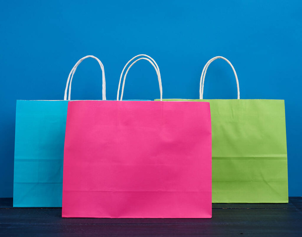 sacs en papier multicolores avec une poignée pour faire du shopping et des cadeaux sur un fond bleu
 - Photo, image
