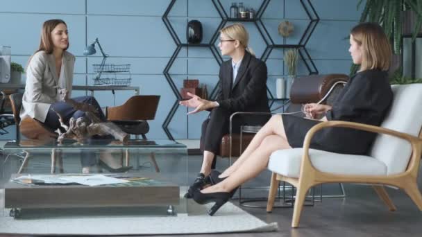 Businesswomen with documents in the office. Three beautiful young girls in business suits are sitting at the office. Tired of work. Communication, cooperation. - Materiał filmowy, wideo