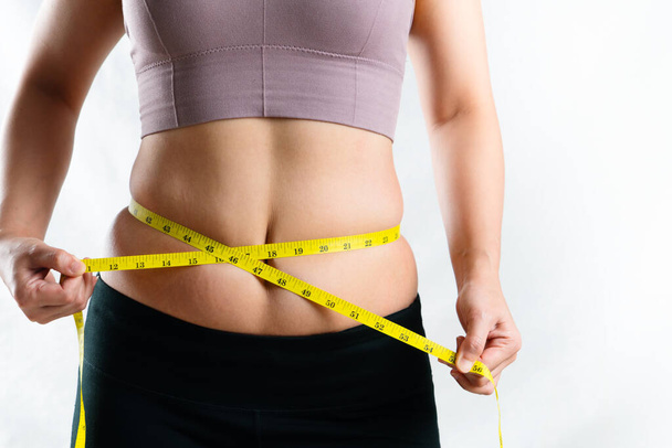 mujer joven que mide su cintura gorda del vientre excesivo con cinta métrica, concepto de estilo de vida de la dieta de la mujer
 - Foto, imagen